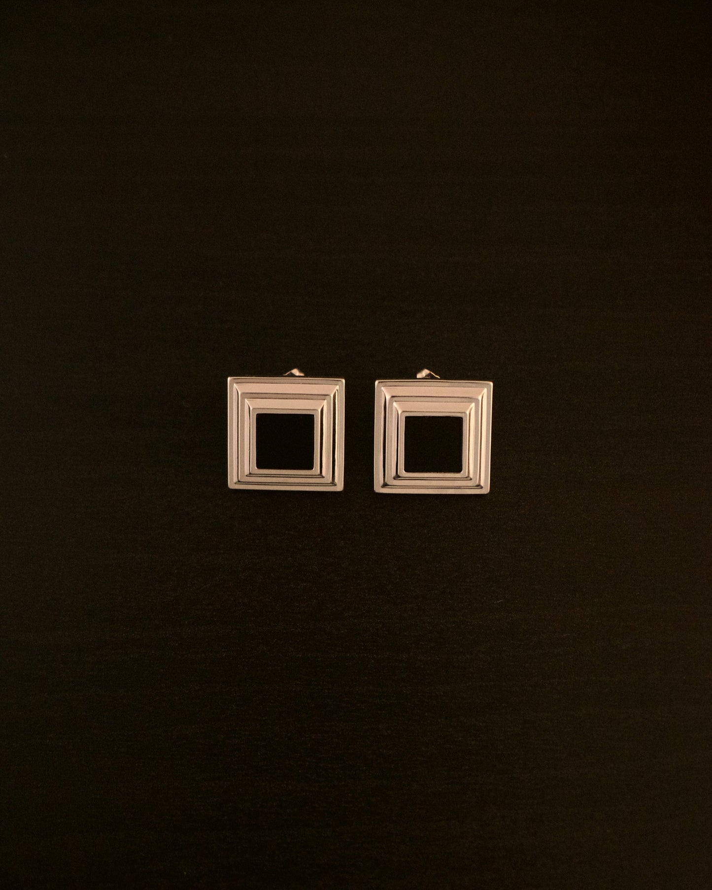 Black Panther earrings – close-up of square silver earrings with a black onyx stone, bold and minimalist design.