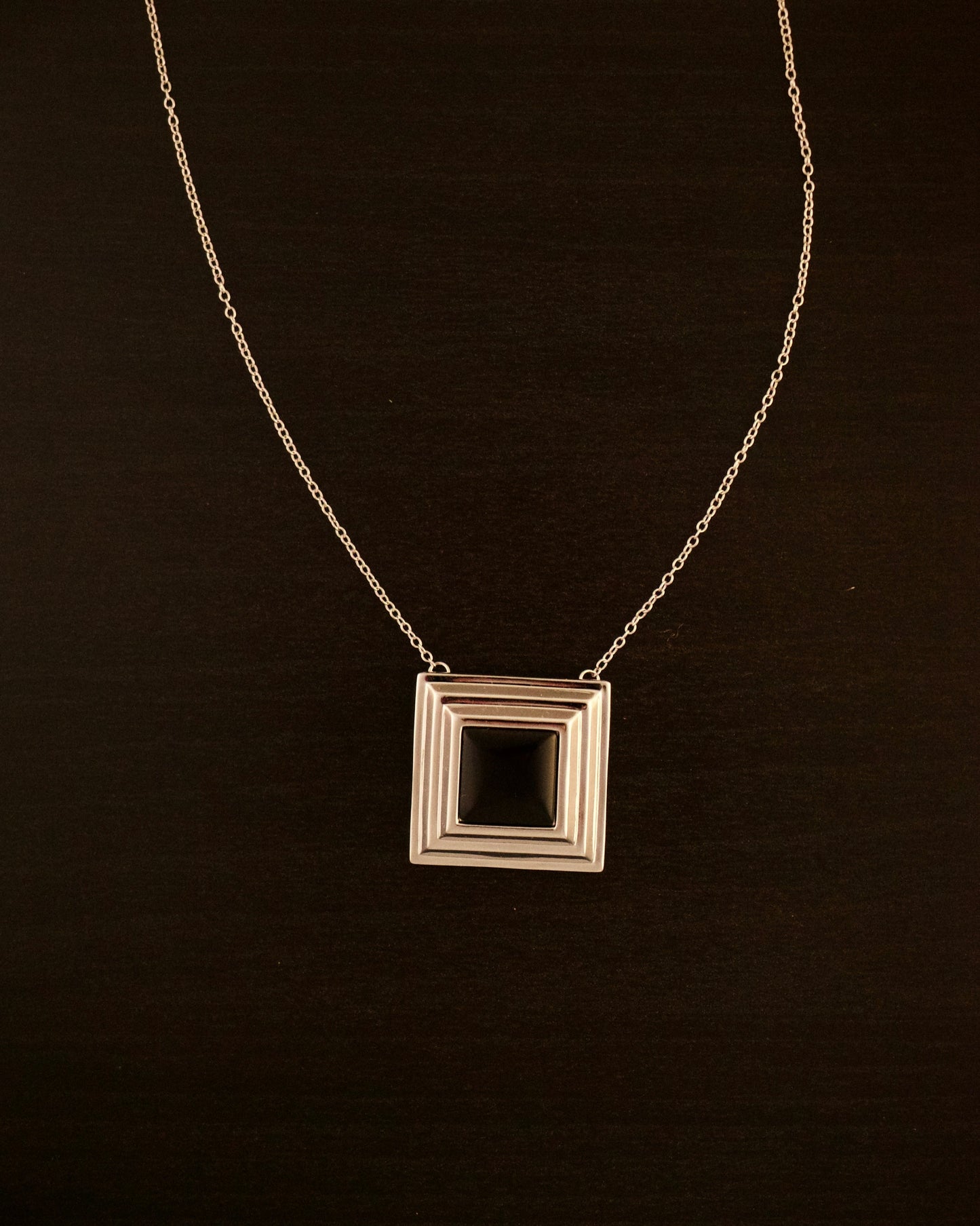 Black Panther necklace – close-up of square silver pendant with a black onyx stone at the center, bold and minimalist.