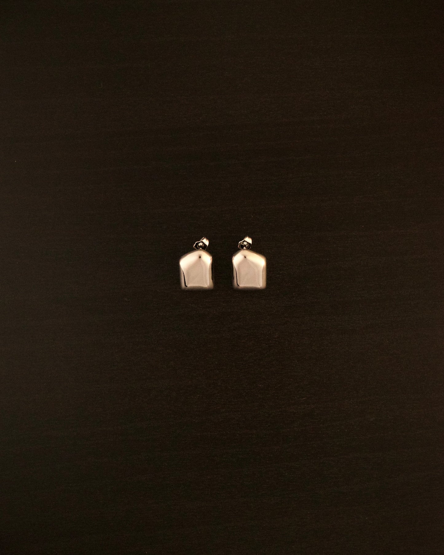 AURA PETITE silver earrings – close-up of sculptural, fluid-shaped minimalist earrings in polished silver.