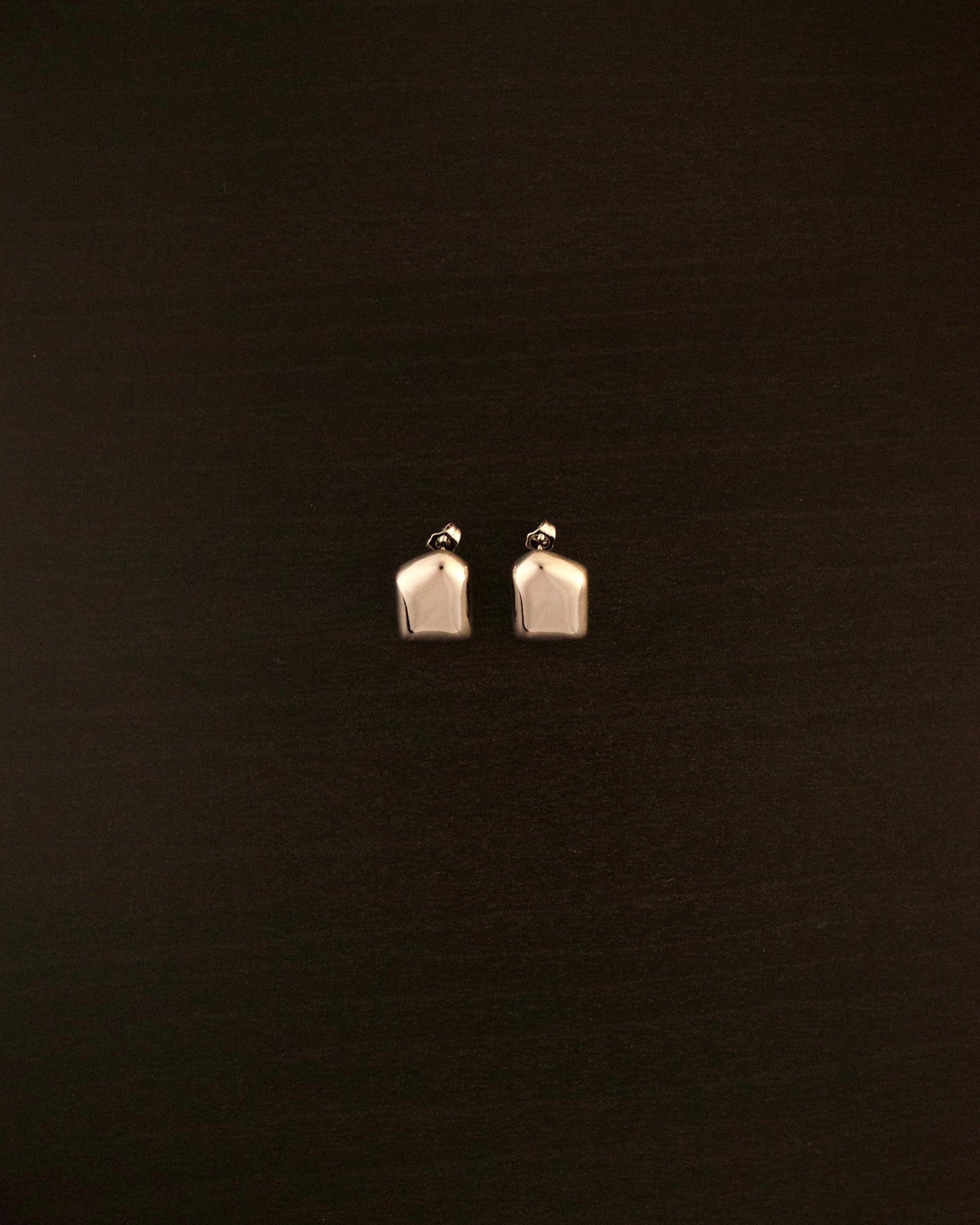 AURA PETITE silver earrings – close-up of sculptural, fluid-shaped minimalist earrings in polished silver.