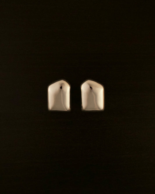 AURA silver earrings – close-up of full-sized sculptural earrings in polished silver with a flowing, organic silhouette.