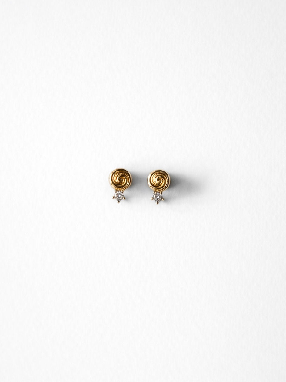 Cold Edges Alba gold spiral stud earrings with a small stone, on a white background