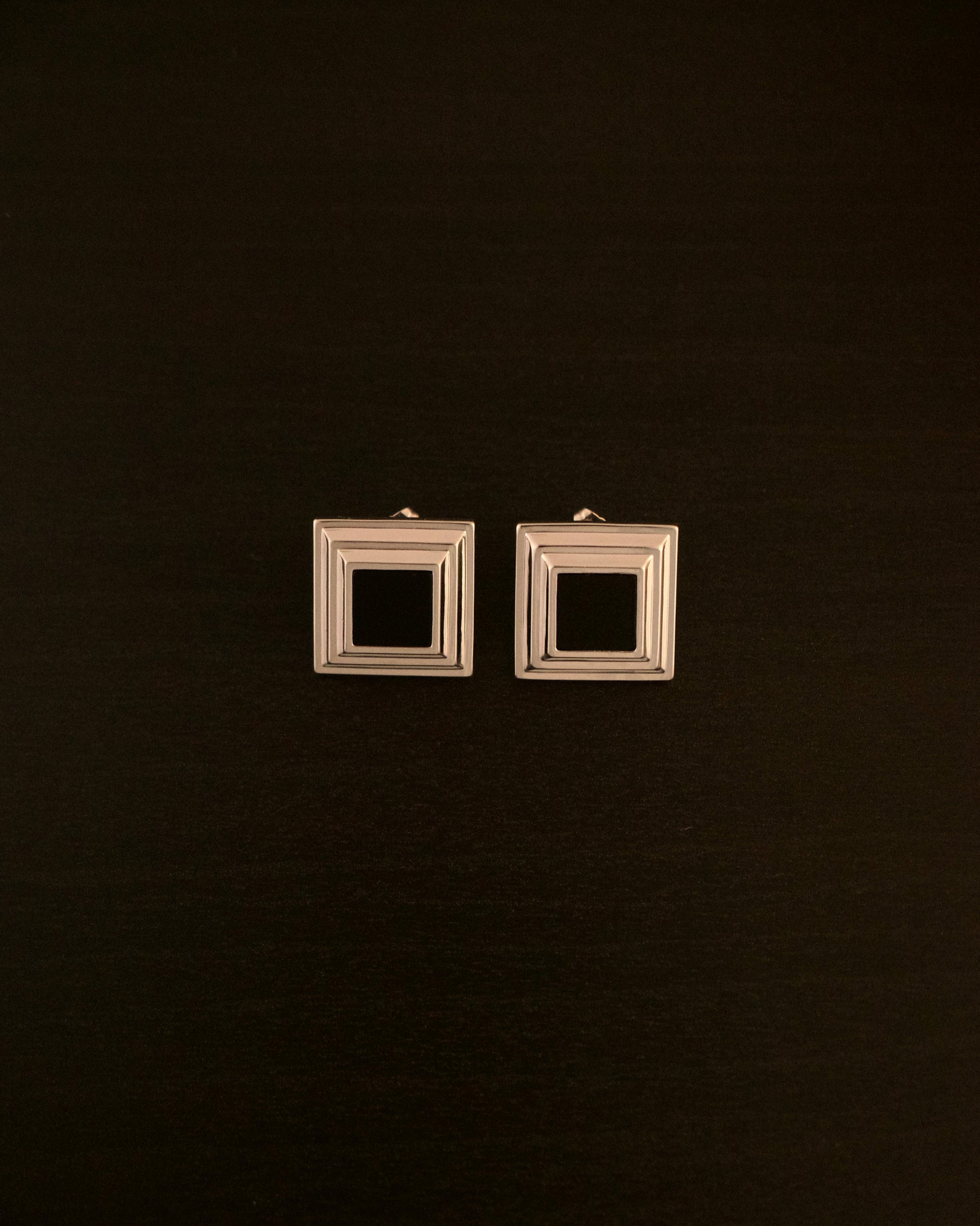 Black Panther earrings – close-up of square silver earrings with a black onyx stone, bold and minimalist design.
