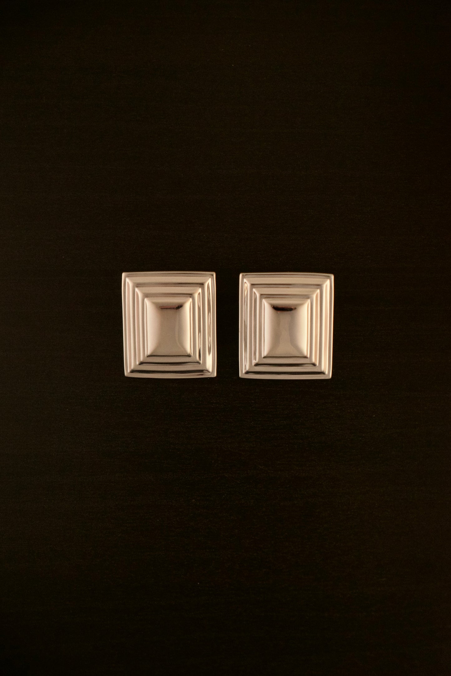 SIENTA silver earrings – close-up of rectangular sculptural earrings in polished silver with a clean, modern design.