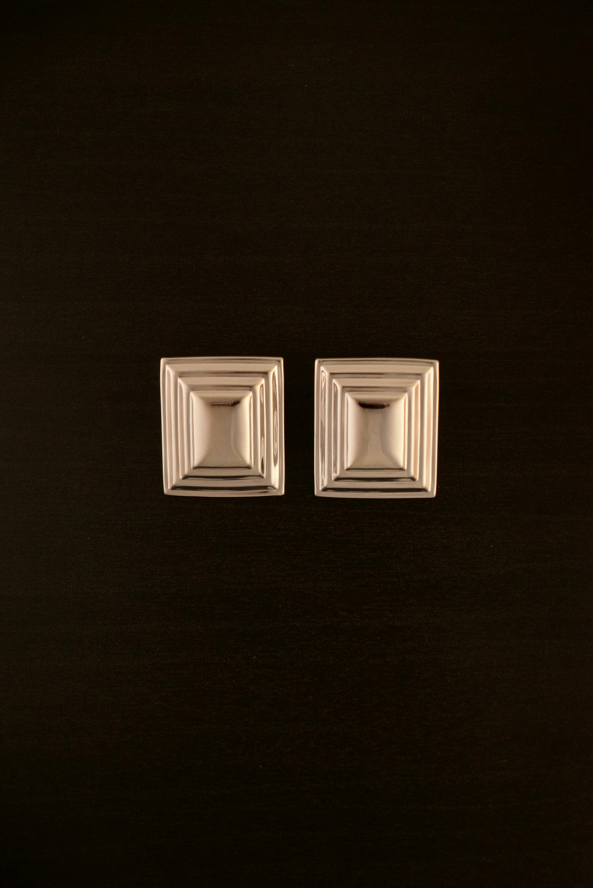 SIENTA silver earrings – close-up of rectangular sculptural earrings in polished silver with a clean, modern design.